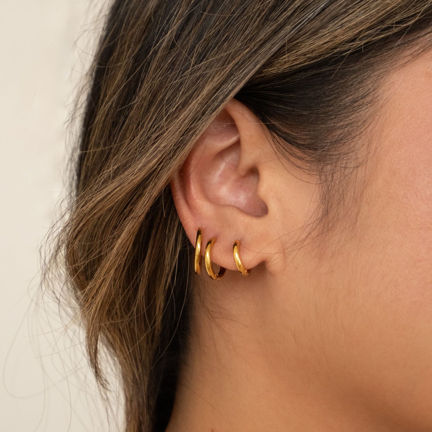 Close-up of an ear wearing gold hoop earrings 