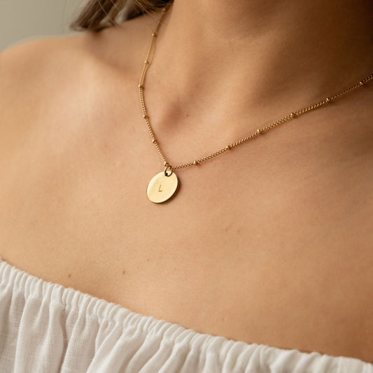 Gold necklace with a round pendant on model
