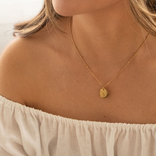 minimal hand stamped pendant necklace worn on model layered dainty jewelry
