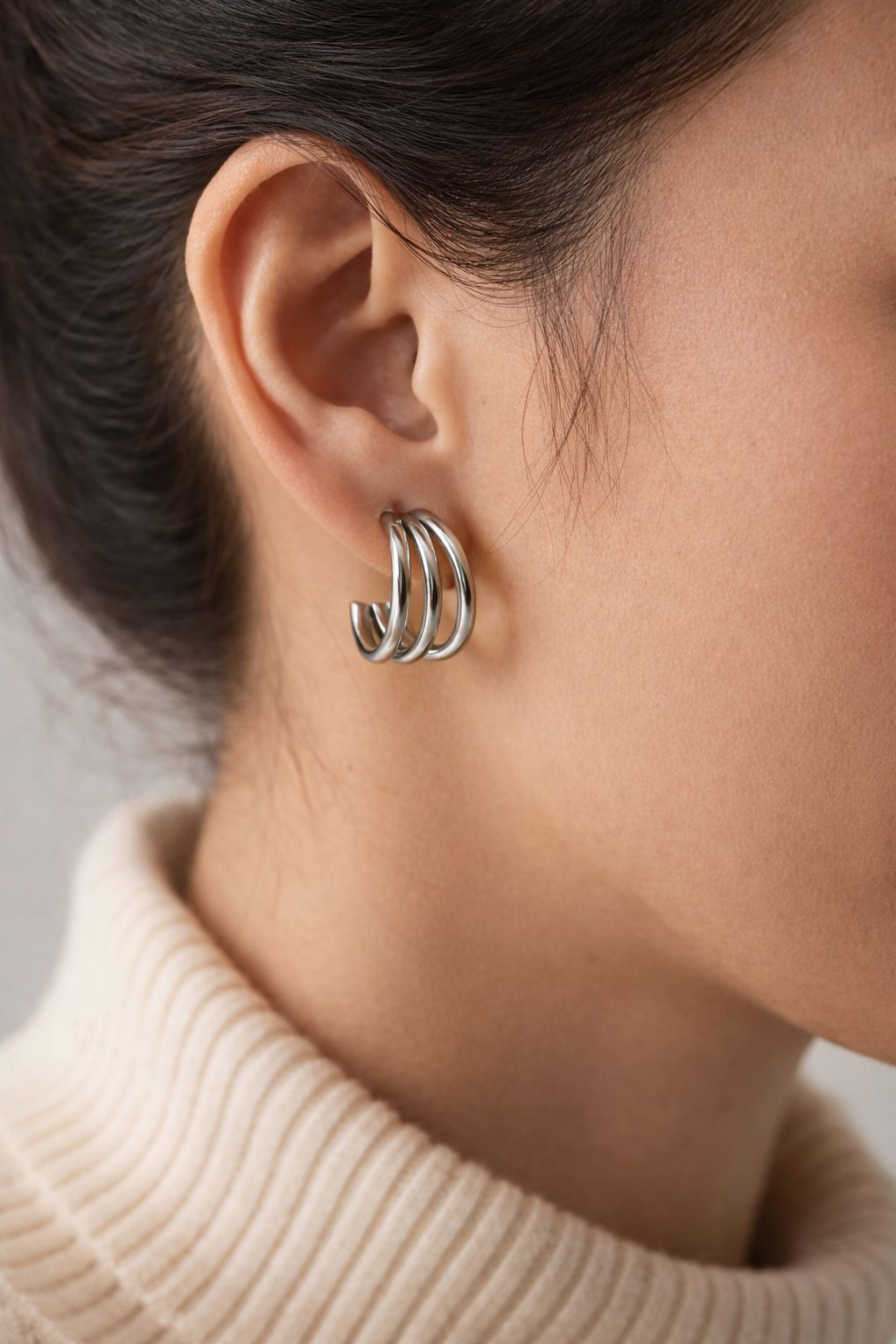 Stainless steel triple hoop earring worn on ear, polished silver finish, minimalist everyday jewelry